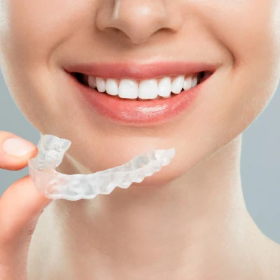 The woman holds transparent aligners